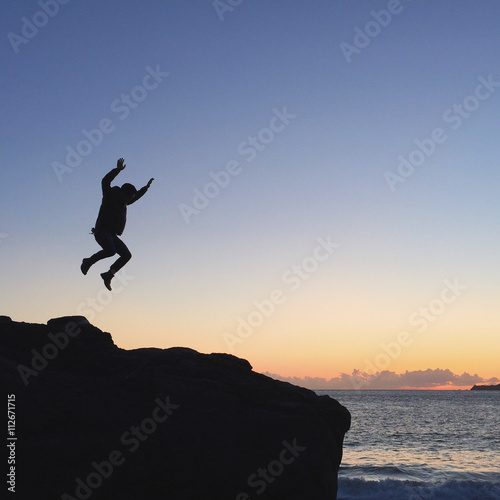 Wallpaper Mural Silhouette of a person jumping on a big rock on a beach Torontodigital.ca
