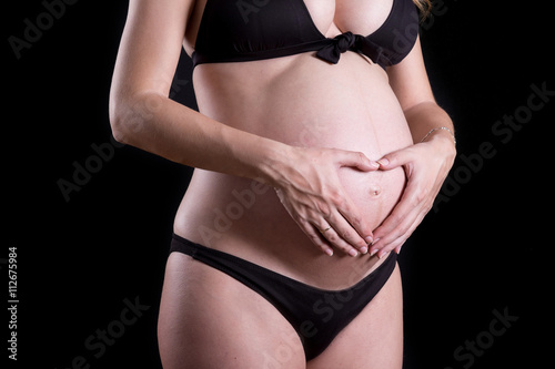 Close up of a cute pregnant belly with black background