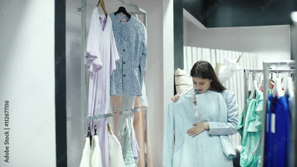 Slow Motion Portrait of shopping woman. Shopper looking at clothes in clothes store. Slow Motion Portrait of shopping woman. Shopper looking at clothes in clothes store.