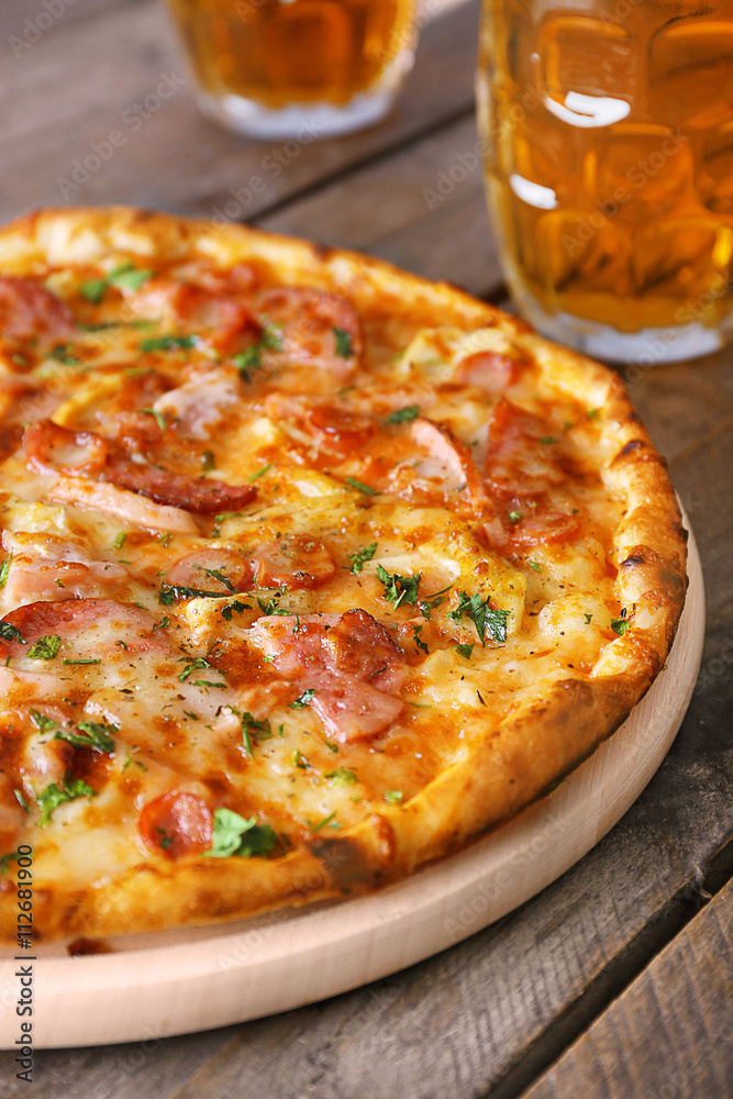 Delicious pizza and glasses of beer are on wooden table, close up Delicious pizza and glasses of beer are on wooden table, close up