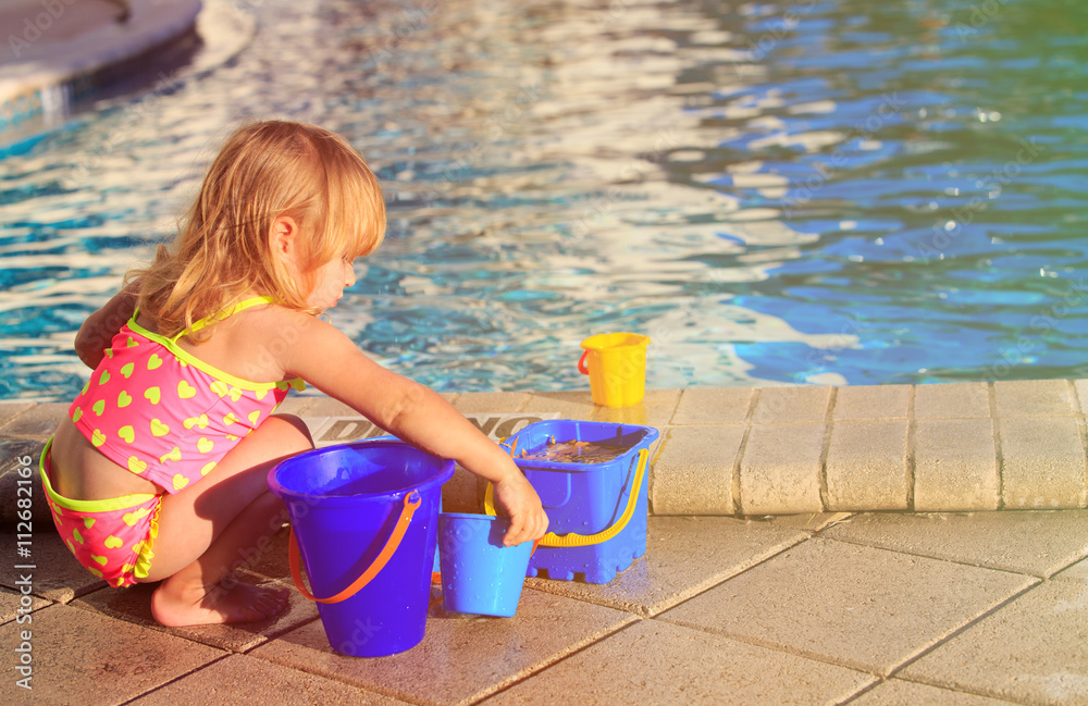 cute little girl playing in swimming pool at beach