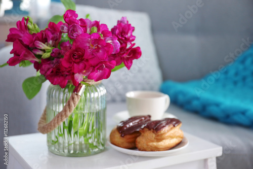 Flowers and pastry on white table in living room