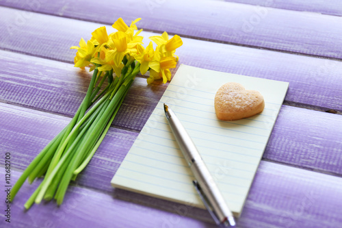 Fototapeta Naklejka Na Ścianę i Meble -  Yellow daffodils and notebook on wooden background