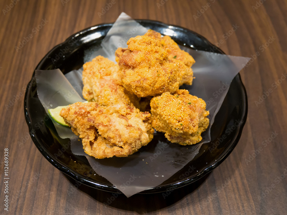 Fresh fried chicken on black plate set on wood table
