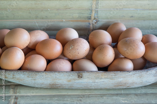 Bunch of chicken eggs in wooden tray.