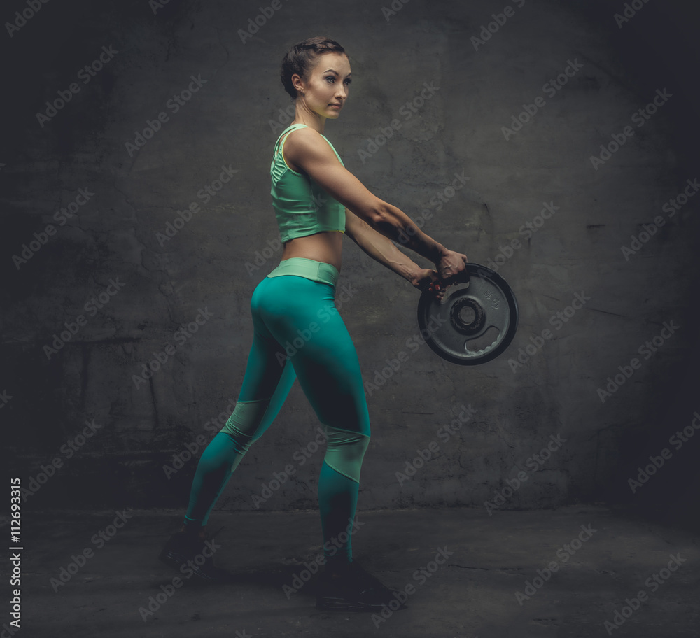 Female in azure sportswear with barbell weight. Female in azure sportswear with barbell weight.