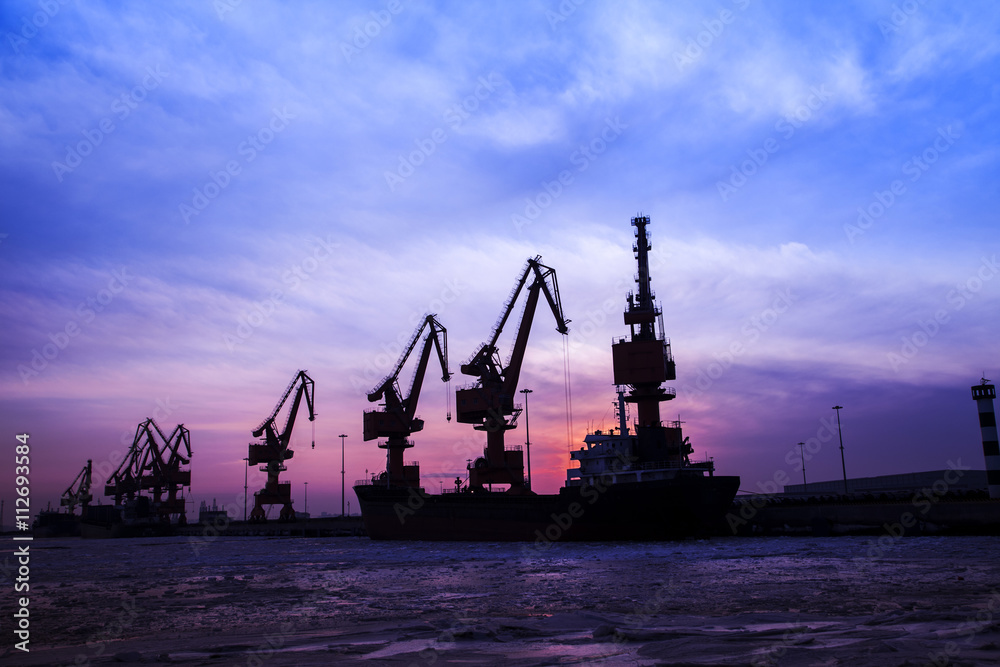 In the evening, the silhouette of port cranes In the evening, the silhouette of port cranes