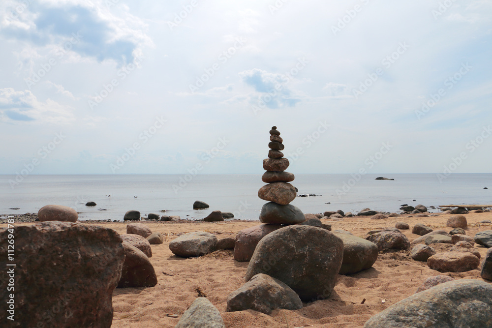 Rock balancing structure on a deserted stony beach against the sea, sky, horizon Rock balancing structure on a deserted stony beach against the sea, sky, horizon