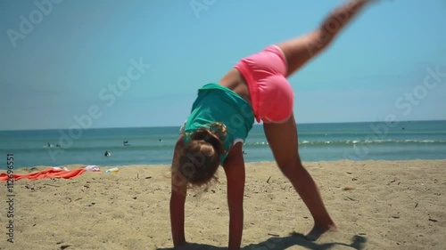 Slow motion of girl doing cartwheel on the sand at beach