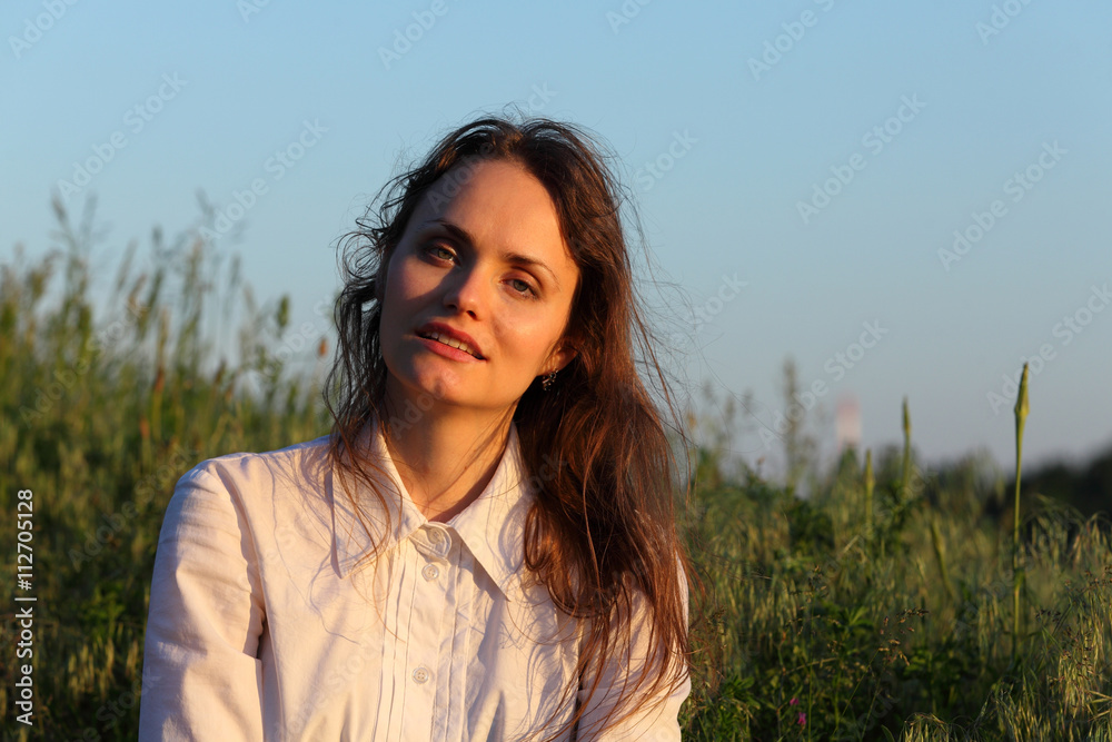 Closeup of a beautiful young woman in nature in evening light