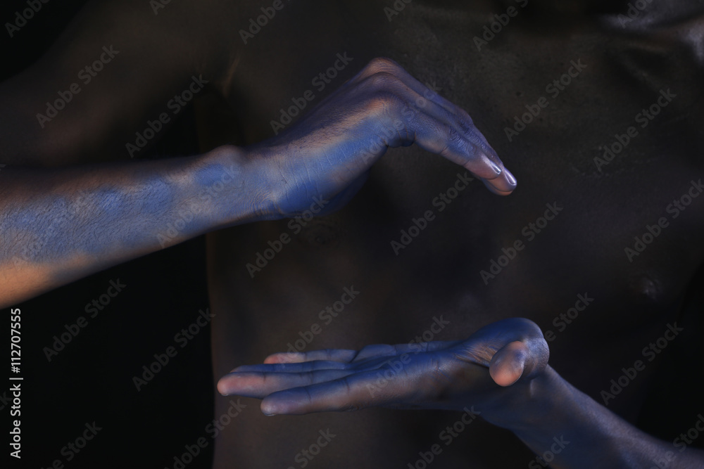 body art tinted black man's hands on the background of male body
