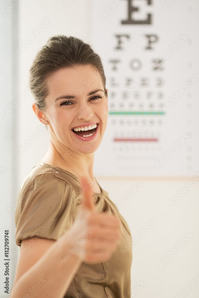 Happy young woman showing thumbs up in front of Snellen chart Happy young woman showing thumbs up in front of Snellen chart
