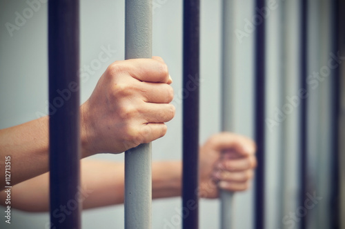 Print op canvas prisoner was locked in jail, hands hold captive iron bars