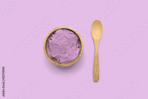 Homemade taro ice cream in wooden bowl with spoon on purple background photo