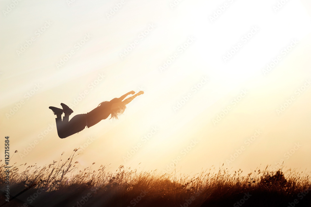 Woman flying over the meadow nature on sunset silhouette background Woman flying over the meadow nature on sunset silhouette background
