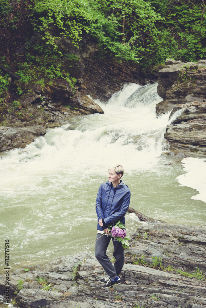 Obraz premium Happy young traveler woman hiking travelling in the forest on a sunny day. Beautiful blond hipster girl outdoors in the forest mountains near river
