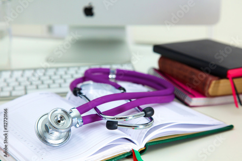 Stethoscope lying on a table on an open book