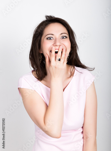 Close up portrait happy young beautiful brunette woman closes mouth by hand. Shocked surprised stunned. Positive human emotion. girl flirting concept