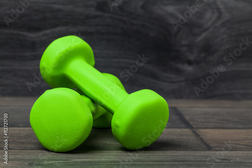Green dumbbell exercise weights on dark wood background