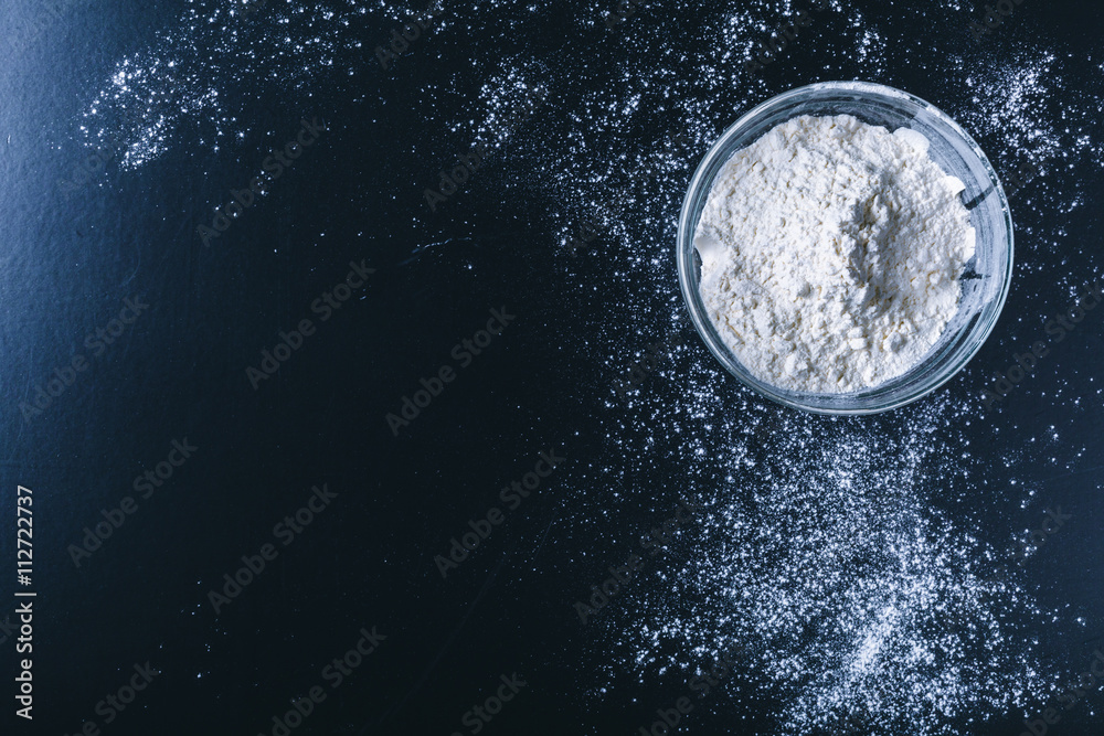 white flour sprinkled on a dark wooden table. top view white flour sprinkled on a dark wooden table. top view