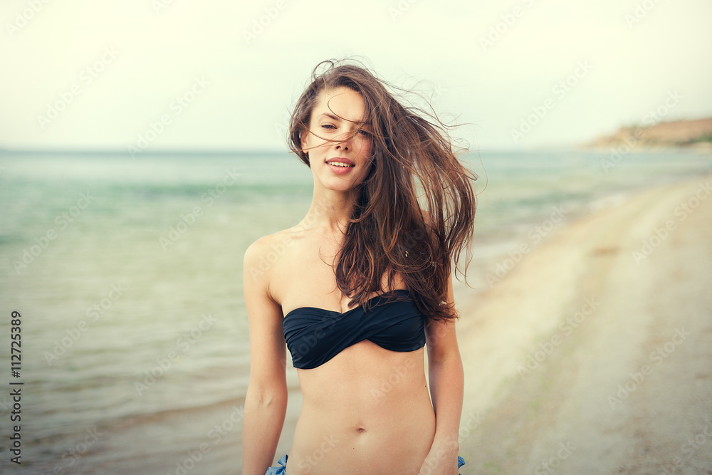 young smiling woman in black bikini on sea background