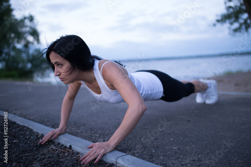 Sporty woman push up at river in twilight