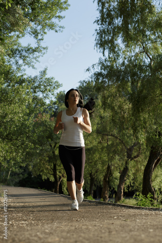 Sporty young woman listening to music while running outdoors