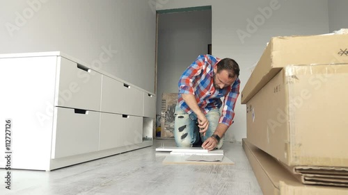 Young man matching furniture with screwdriver on floor at home
