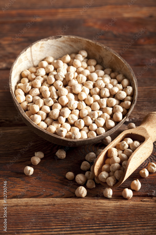 Chickpeas in bowl and scoop on wooden table Chickpeas in bowl and scoop on wooden table