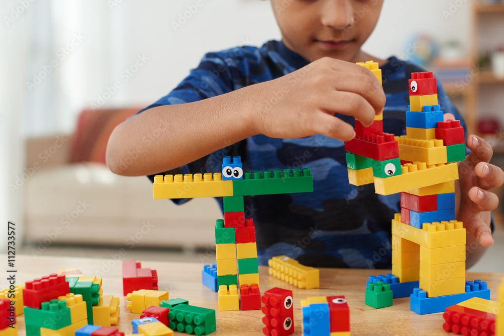 Fototapeta premium Cropped image of child making creatures out of plastic bricks