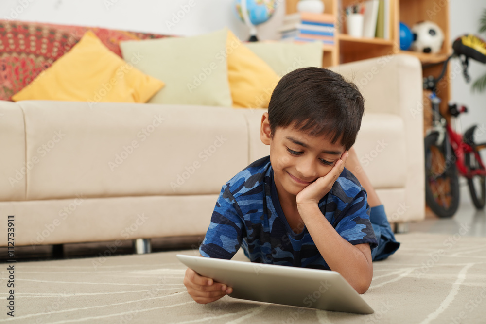 Smiling Asian boy watching cartoon on digital tablet Smiling Asian boy watching cartoon on digital tablet