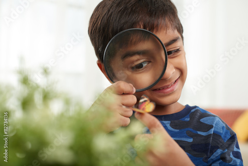 Smiling child looking at butterfly through magnifying glass