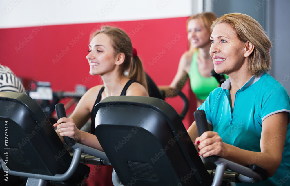 Positive elderly and young women working out in gym