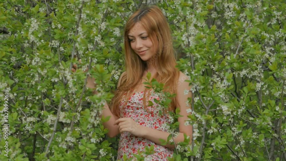 girl smiles against a background of flowering branches in spring