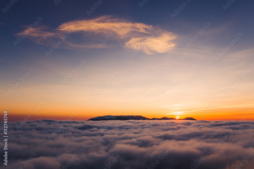 Beautiful sunset on the hill above clouds