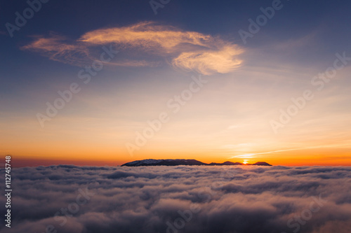 Beautiful sunset on the hill above clouds