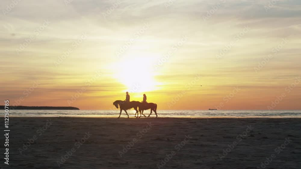Silhouette of Two Riders on Horses at Beach in Sunset Light. Shot on RED Cinema Camera. Silhouette of Two Riders on Horses at Beach in Sunset Light. Shot on RED Cinema Camera.