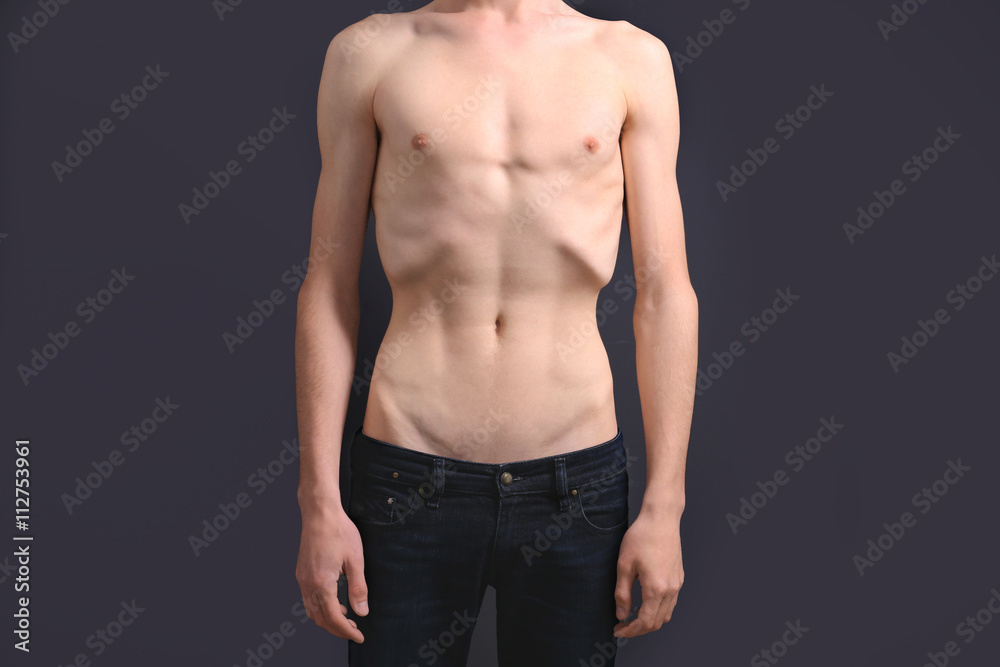 Skinny young man with anorexia on dark background