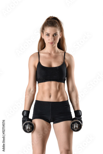 Cutout fitness model wearing sportswear stands looking directly at the camera, holding dumbells.