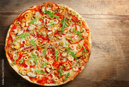 Pizza with seafood, red pepper and green olives on wooden table #112755512