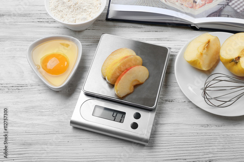 Making apple pie. Using digital kitchen scales on wooden table. Cooking apple cake concept photo