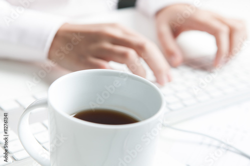 Frau tippt auf Tastatur, Kaffeetasse