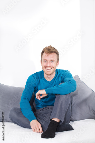 Junger Mann sitzt auf Couch, entspannt, relaxed, Freizeit