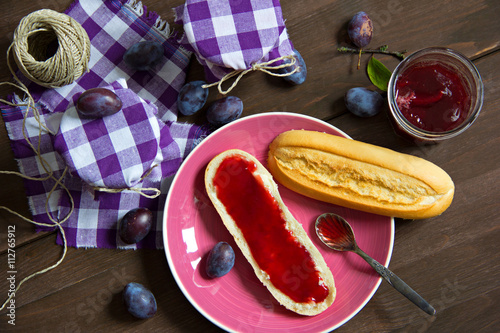 Zwetschgenmarmelade in Gläsern und Baguettebrötchen mit Marmel photo