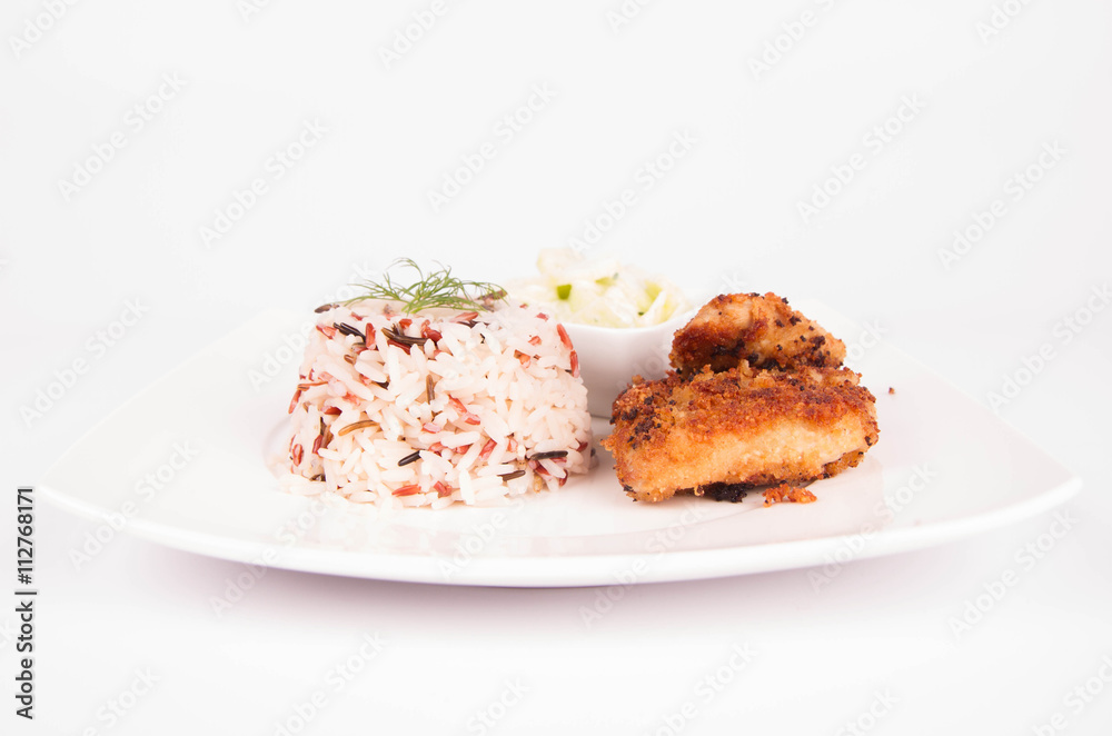 Pork chop (covered in breadcrumbs), three color rice and cucumber salad decorated with dill on a plate on white background