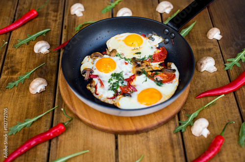 Pan of fried eggs, bacon and tomatoes