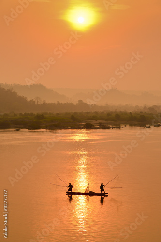 Siluate fisherman casting a net into the water during on the mist at
