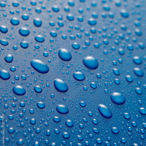 Glistening water droplets on waxed blue metal