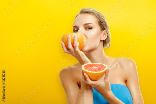 Young woman with fruits on bright orange background