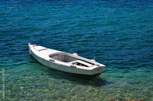 Tiny wooden boat on an azure sea © Kazick